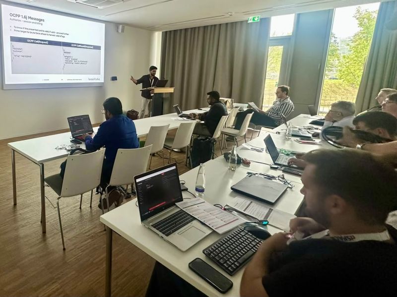 Gagan presenting at the EV Charger Hacking workshop, attendees working on laptops